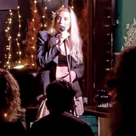 Rachel Sheen is performing with a mic as people around are watching.